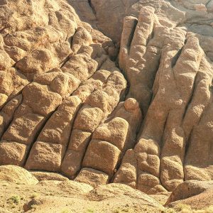 "A stunning view of the Monkey’s Fingers in Morocco’s Dades Valley, where towering rock formations rise like giant fingers reaching for the sky. The warm reds, oranges, and ochres of the cliffs contrast beautifully with the bright blue sky and green valley below. The landscape feels magical, with winding trails, narrow canyons, and boulders to climb. As you explore, you can spot small Berber villages tucked into the valley, adding a sense of timeless culture to the natural beauty.